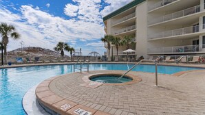 Ein Pool mit Whirlpool, umgeben von einer Pflasterterrasse und Palmen.