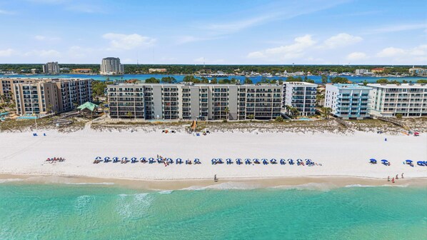 A beachfront hotel with multiple buildings, a sandy beach, and clear turquoise waters. - Getaway with beautiful Gulf-front view, pool, gym & seasonal beach service (Fort Walton Beach)