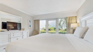 Une chambre d’hôtel avec un grand lit, un téléviseur posé sur une commode et une vue sur la verdure.