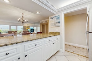A spacious kitchen with a granite countertop, white cabinetry, and a chandelier. - Cozy, Gulf-front home with 2 beach chairs - short distance to entertainment (Miramar Beach)