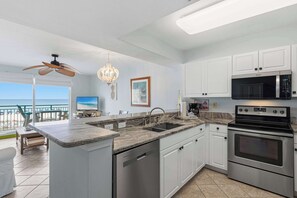 A modern kitchen with a large island, stainless steel appliances, and a view to the outside. - 3rd-floor, Gulf-front condo with seasonal beach setup - near entertainment (Fort Walton Beach)