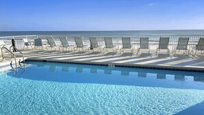 Piscina cristallina con lettini e vista sull'oceano.
