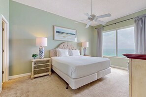 A bedroom with a bed, nightstands, a ceiling fan, a window with curtains, and a framed picture on the wall. - Gorgeous home a walk to the Gulf & minutes from dining (Miramar Beach)