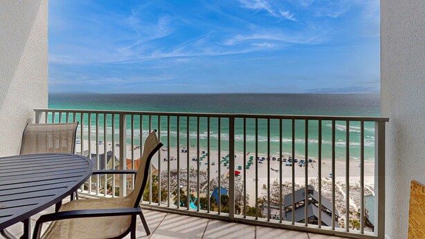 Un balcone con vista sulla spiaggia, un tavolo e sedie.