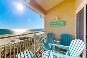 Un balcón con sillas Adirondack turquesas, un letrero que dice "Beach Lovers" y vista a la playa y al océano.