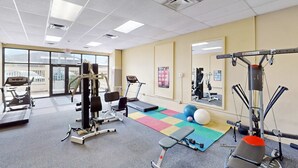 A gym with cardio machines, weight training equipment, a colorful mat, and a mirror. - Gulf-view condo with furnished balcony, pools, beach access, fitness room (Panama City Beach)