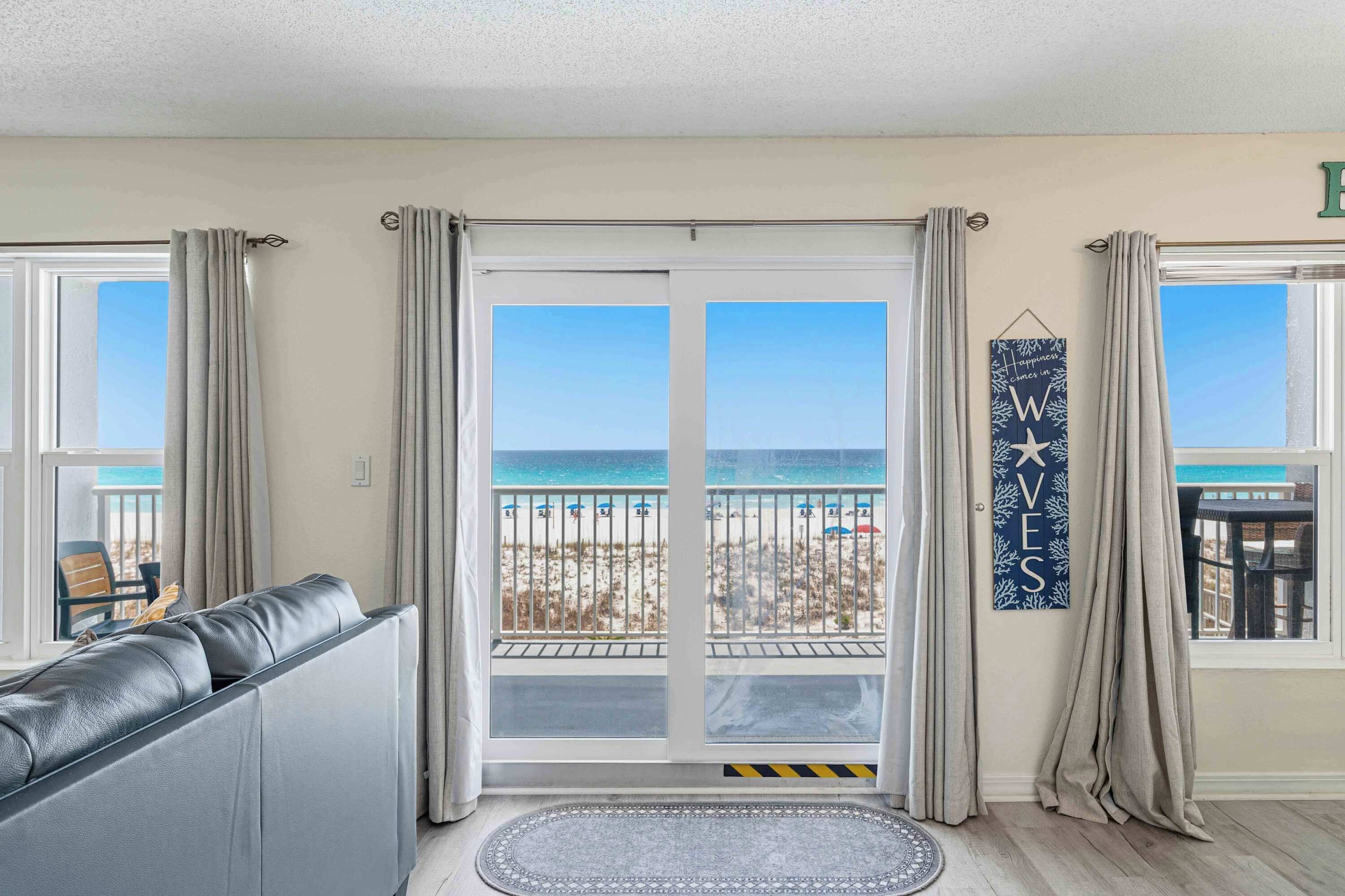 Une chambre avec vue sur la plage, une porte-fenêtre coulissante, un canapé et un panneau décoratif.