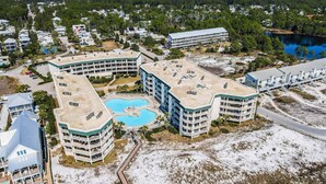 Ein mehrstöckiges Hotel mit Pool auf dem Dach und einer gepflegten Grünanlage.