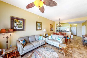 A living room with a sofa, a round coffee table, and a dining area with chairs.