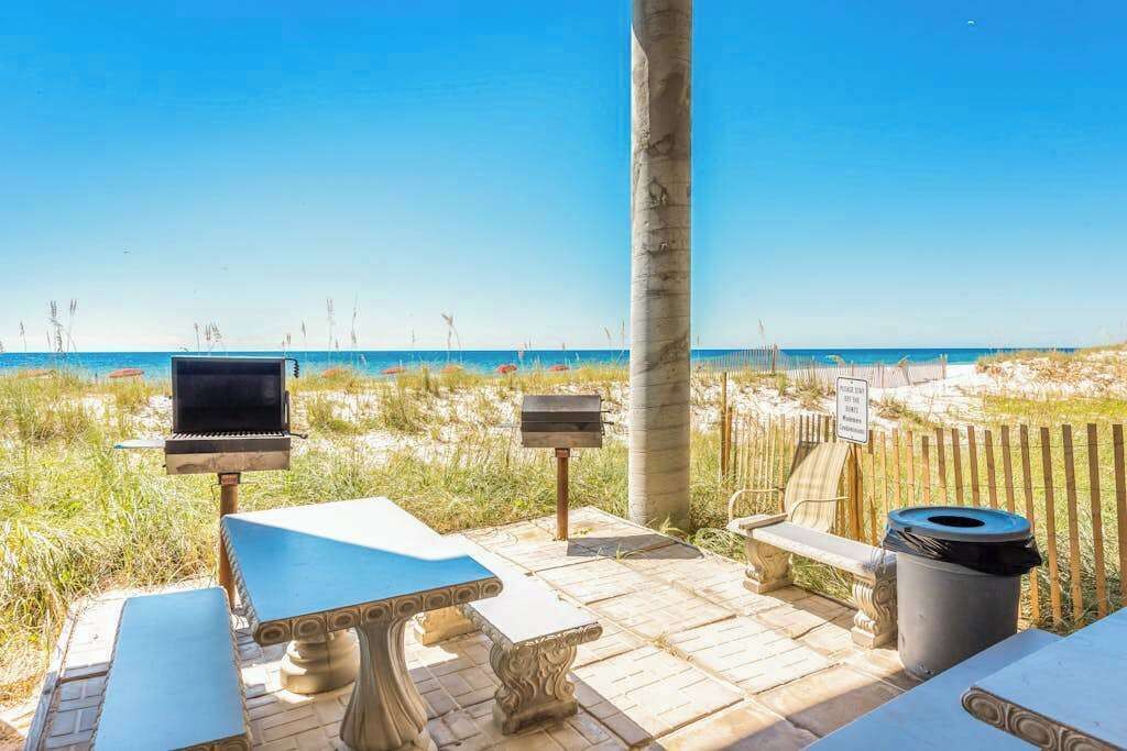 An outdoor seating area with a grill, a trash bin, and a bench.