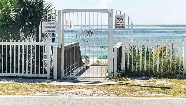 A gated entrance with a sign indicating private property and surveillance. - Condo with Pool Amenity in Miramar Beach (Miramar Beach)