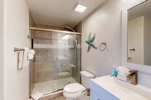 Een moderne badkamer met een douchecabine, een toilet en een wastafel met toiletartikelen.