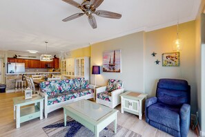 A living room with a sofa, armchairs, a coffee table, and a ceiling fan. - Snowbird friendly gulf-view condo w/ Pool  Hot tub, & Private Balcony (Panama City Beach)