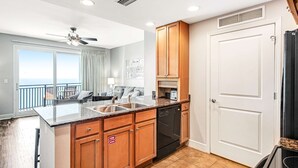 Een moderne keuken met houten kastjes, een inbouwvaatwasser en een groot raam met uitzicht op een balkon.