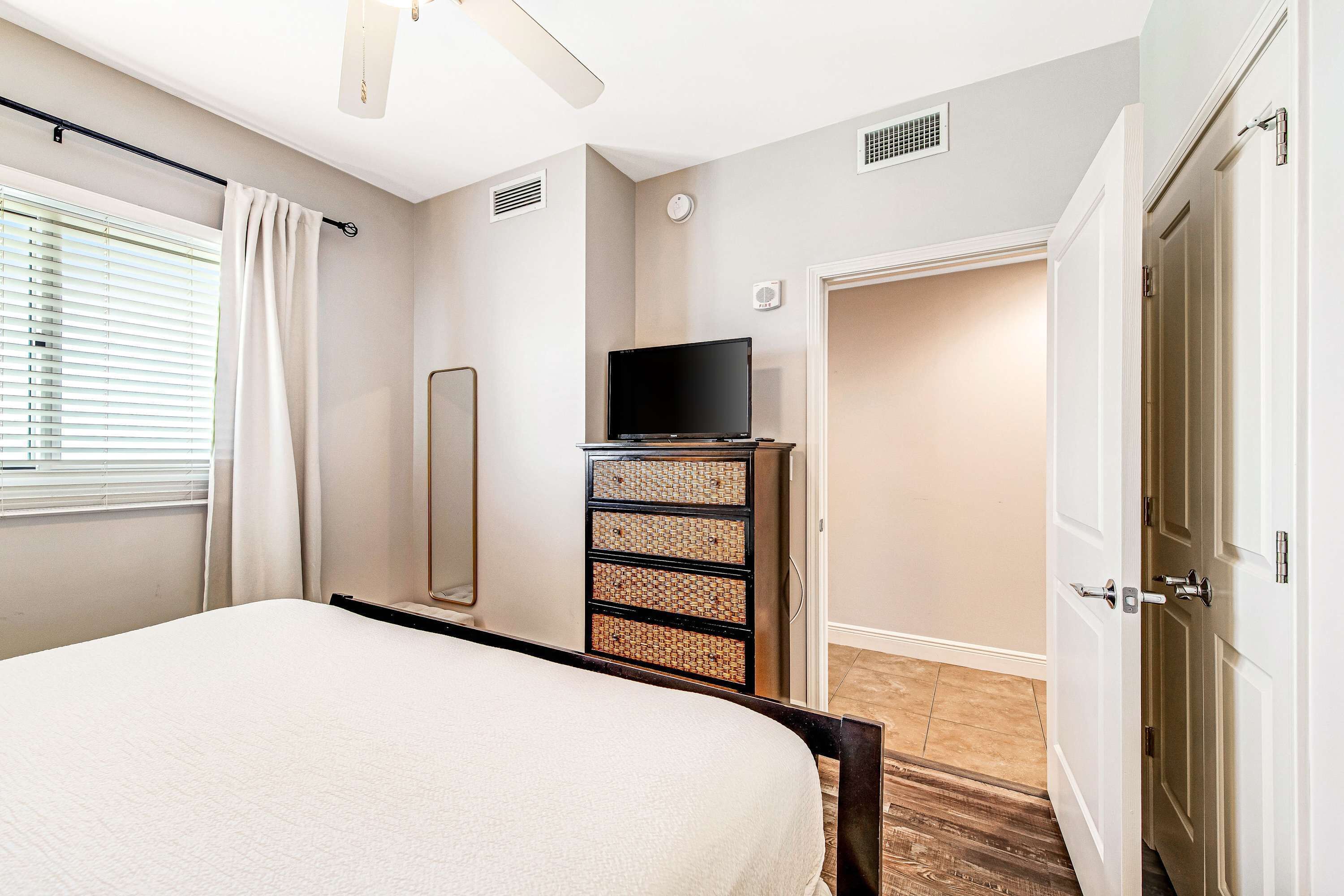 Een slaapkamer met een bed, een dressoir, een televisie en een deur.