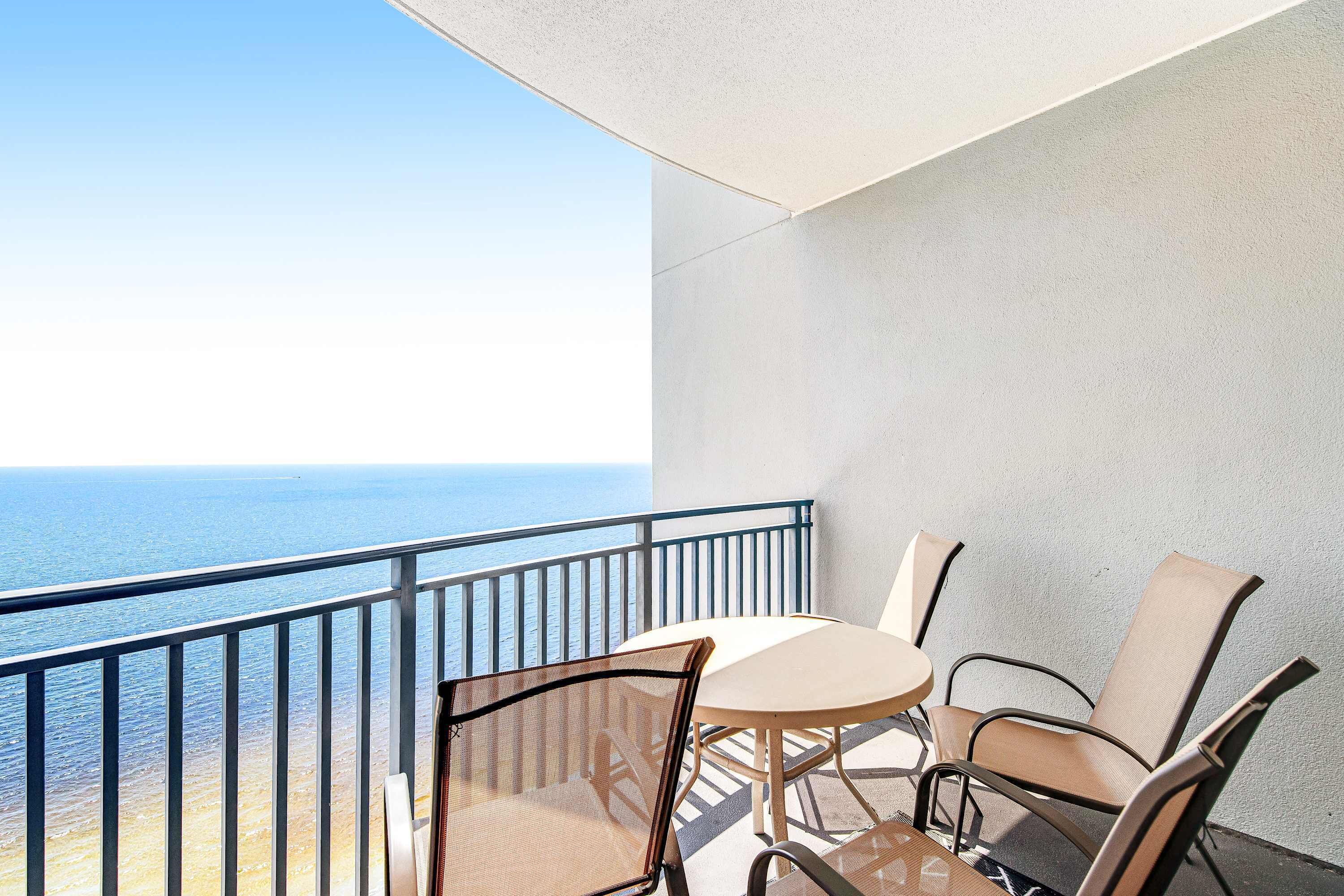Ein Balkon mit Tisch und Stühlen mit Blick aufs Meer.