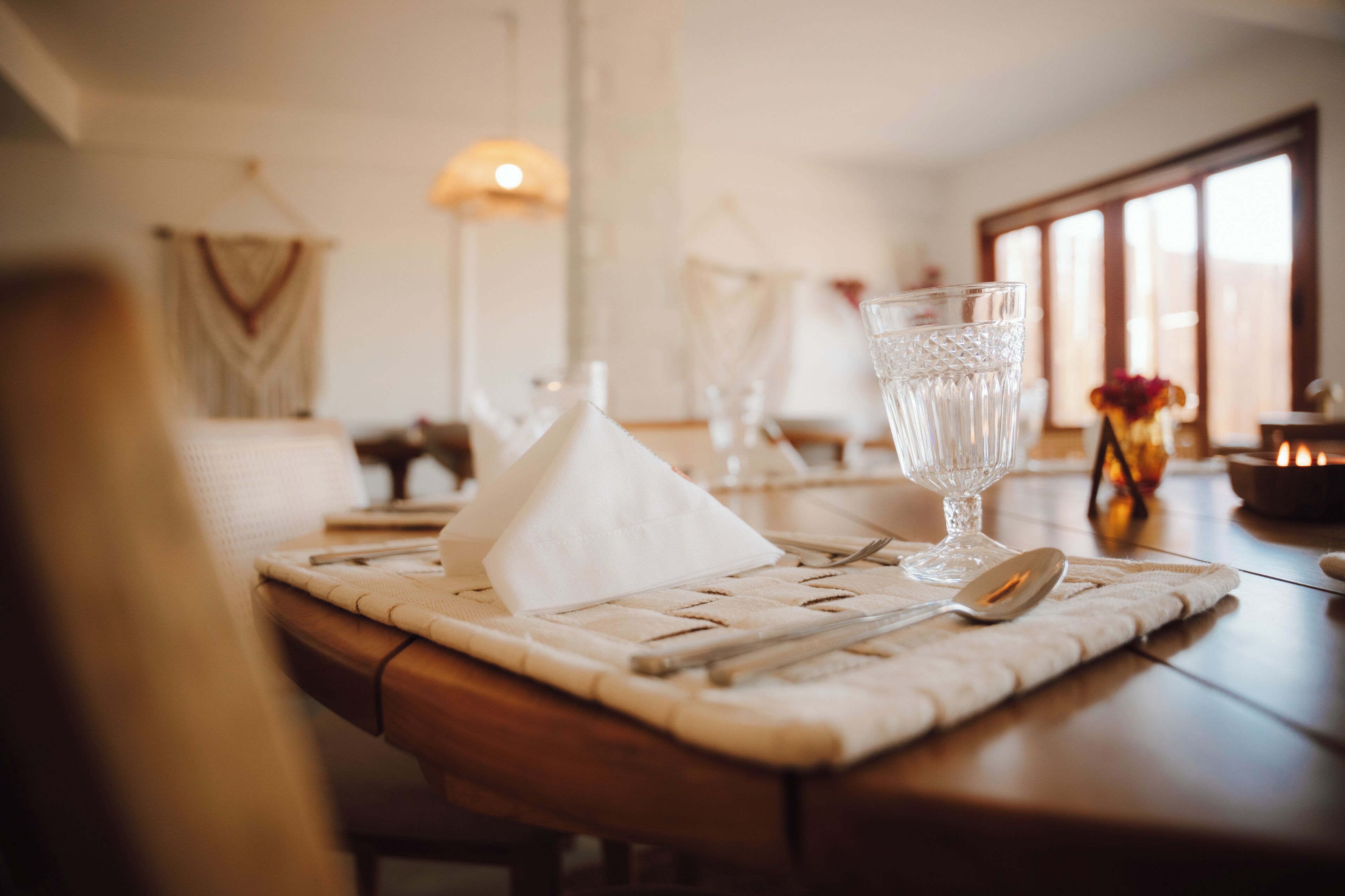 A dining table set with a glass of water, a napkin, and cutlery.