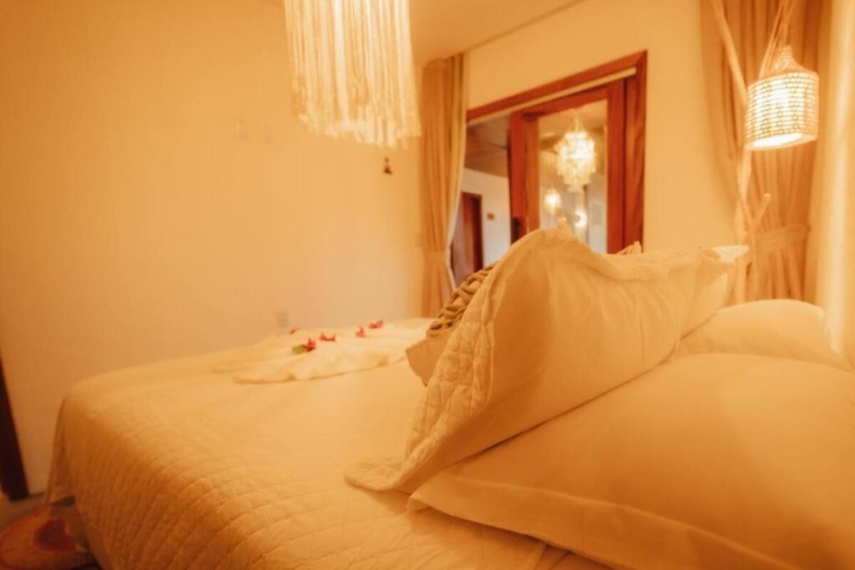 Een hotelkamer met een bed, een spiegel en een hanglamp.