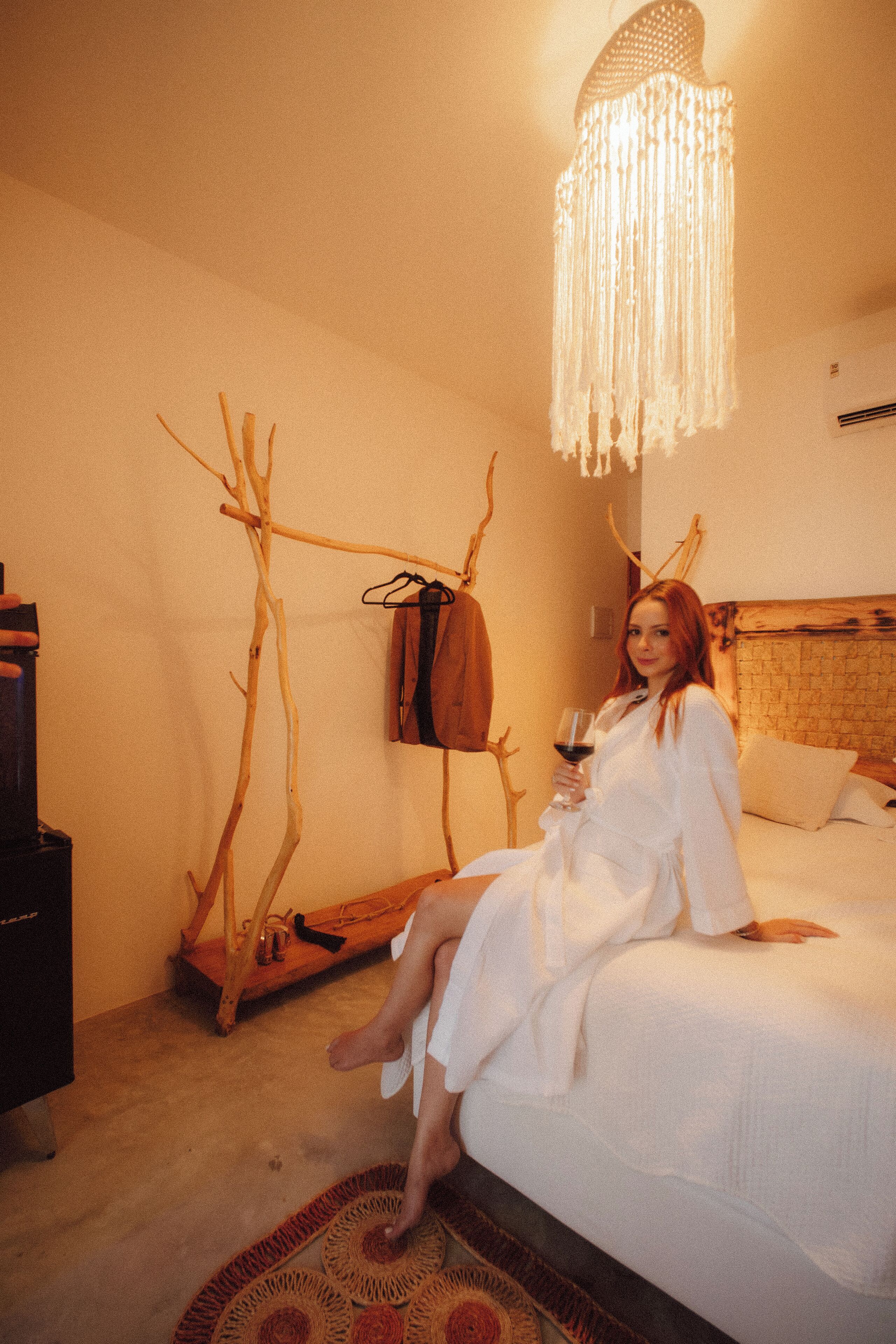 A room with a bed, a hanging light fixture, and a coat rack.