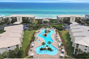 Een resort met een centraal gelegen zwembad, meerdere gebouwen en uitzicht op het strand.