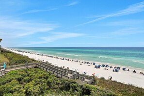 Ein Strand mit einer Holzpromenade, die zum Ufer führt, strahlend blauem Himmel und ruhiger See.
