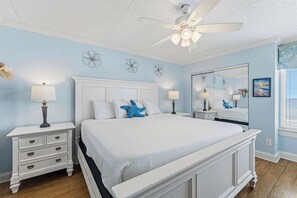 A bedroom with a large bed, two bedside tables with lamps, a ceiling fan, and a large mirror. - Comfortable waterfront condo with beach chairs - close to dining (Fort Walton Beach)