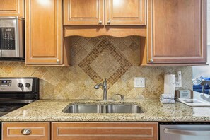 A kitchen with wooden cabinets, a granite countertop, stainless steel appliances, and a diamond-patterned backsplash. - Comfortable waterfront condo with beach chairs - close to dining (Fort Walton Beach)