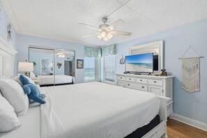 A bedroom with a bed, a television, a ceiling fan, and a macrame wall hanging. - Comfortable waterfront condo with beach chairs - close to dining (Fort Walton Beach)
