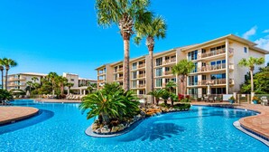 Un hotel con piscina rodeada de palmeras y sillas de descanso.