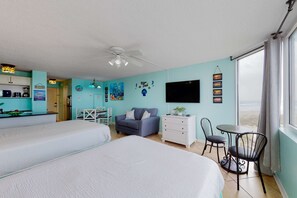 A room with two beds, a desk, a chair, a TV, and a window with a view.