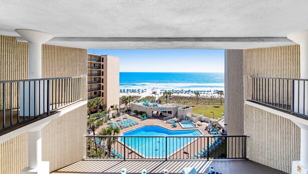 A balcony with a view of a pool and beach.