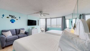 A hotel room with a large bed, a sofa, a desk, and a TV.