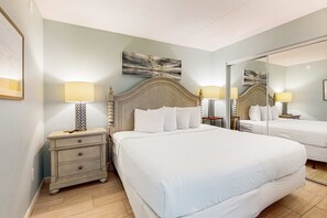 A hotel room with a large bed, two bedside tables with lamps, a mirror, and a painting on the wall. - 6th-floor, cozy beachfront condo with views - quick walk to dining (Fort Walton Beach)
