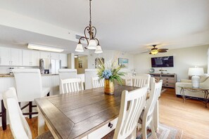 A modern kitchen with white cabinets, a wooden dining table, and a ceiling fan. - Cozy oceanfront condo with ocean view, pool access, washer&dryer, and central AC (Fort Walton Beach)