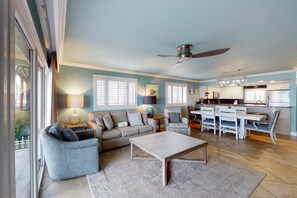 A modern living room with a sofa, coffee table, and dining area. - Gorgeous beachfront condo with a pool & private beach access (Miramar Beach)