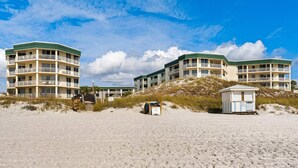 Un hotel sulla spiaggia con numerosi balconi e una piccola capanna.