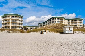 A beachfront hotel with multiple balconies and a small beach hut. - Gulf-front view & spacious condo with wraparound balcony & pickleball (Santa Rosa Beach)