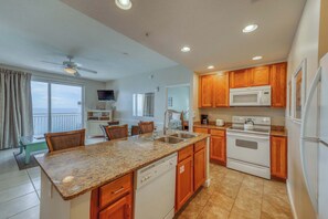 A kitchen with granite countertops, wooden cabinets, a dishwasher, a microwave, and an oven. - Waterfront condo with a balcony overlooking the Gulf, pool & a gym (Panama City Beach)