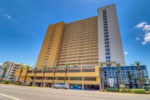 A multi-story hotel with a modern design, featuring a prominent entrance and a parking area. - Gulf-front condo with free beach service, balcony & pool (Panama City Beach)