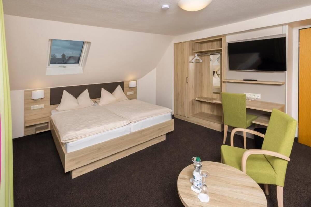 A hotel room with a bed, bedside tables, a TV, a desk with a chair, and a window with a view.