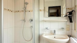 A bathroom with a shower, sink, and mirror. - Landhotel Wolf-Mertes (Sessenbach)