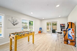 A spacious room with a foosball table, a basketball arcade, and a large window with blinds. - Modern home with WiFi, deck, washer & dryer and central AC (Perdido Key)