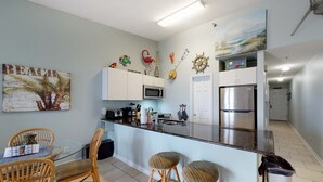 Eine moderne Küche mit weißen Schränken, einem Edelstahl-Kühlschrank und einer Bar mit Hockern.