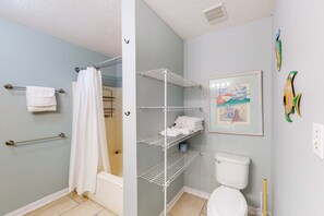 Een badkamer met douche, toilet en opbergplanken.