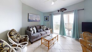 Ein Wohnzimmer mit einer Couch, Sesseln, einem Couchtisch, einem Deckenventilator und einem Fernseher.