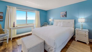 A bedroom with a large bed, a nightstand, a chair, and a window with curtains. - Gorgeous Oceanfront condo with washer/dryer, Gulf-front balcony & pool/hot tub (Perdido Key)