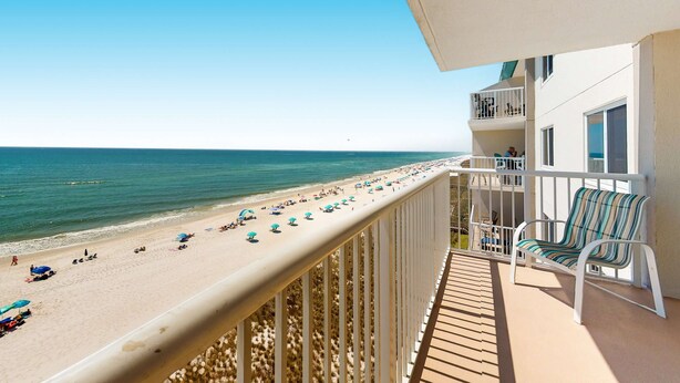 A balcony with a view of a beach, a pool, and a lounge area with chairs. - Gorgeous Oceanfront condo with washer/dryer, Gulf-front balcony & pool/hot tub (Perdido Key)