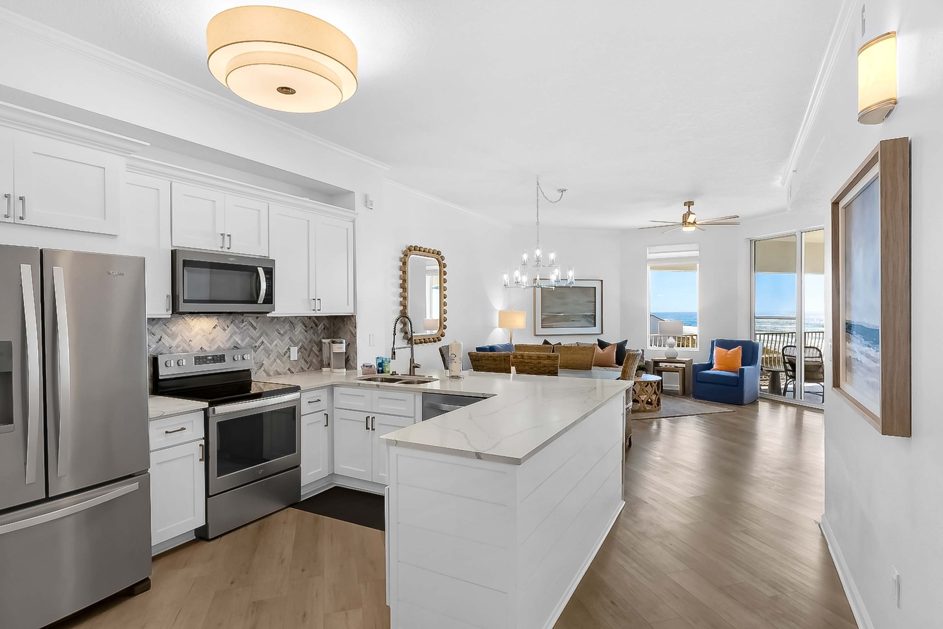 A modern kitchen with white cabinetry, stainless steel appliances, and a marble backsplash.