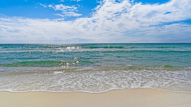 Ein Strand mit klarem, blauem Wasser und einem Sandstrand.