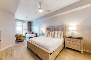 Une chambre à coucher avec un grand lit, une table de chevet, un ventilateur de plafond et une fenêtre.